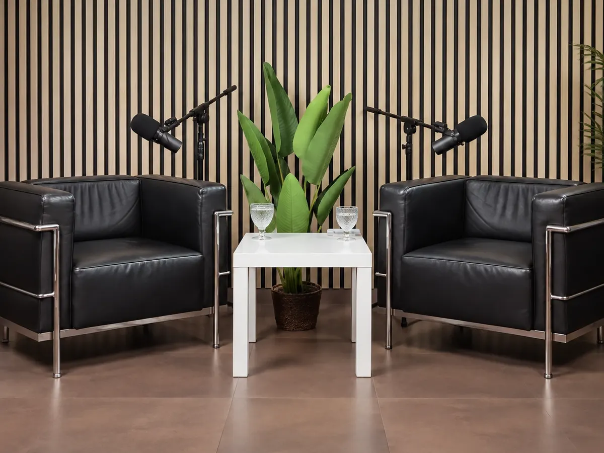 Set del podcast: listones de madera, butacones negros y micros de brazo.